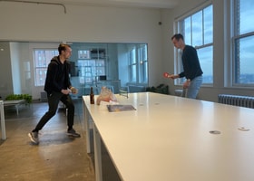 Two Headway employees playing ping pong on a desk in the office